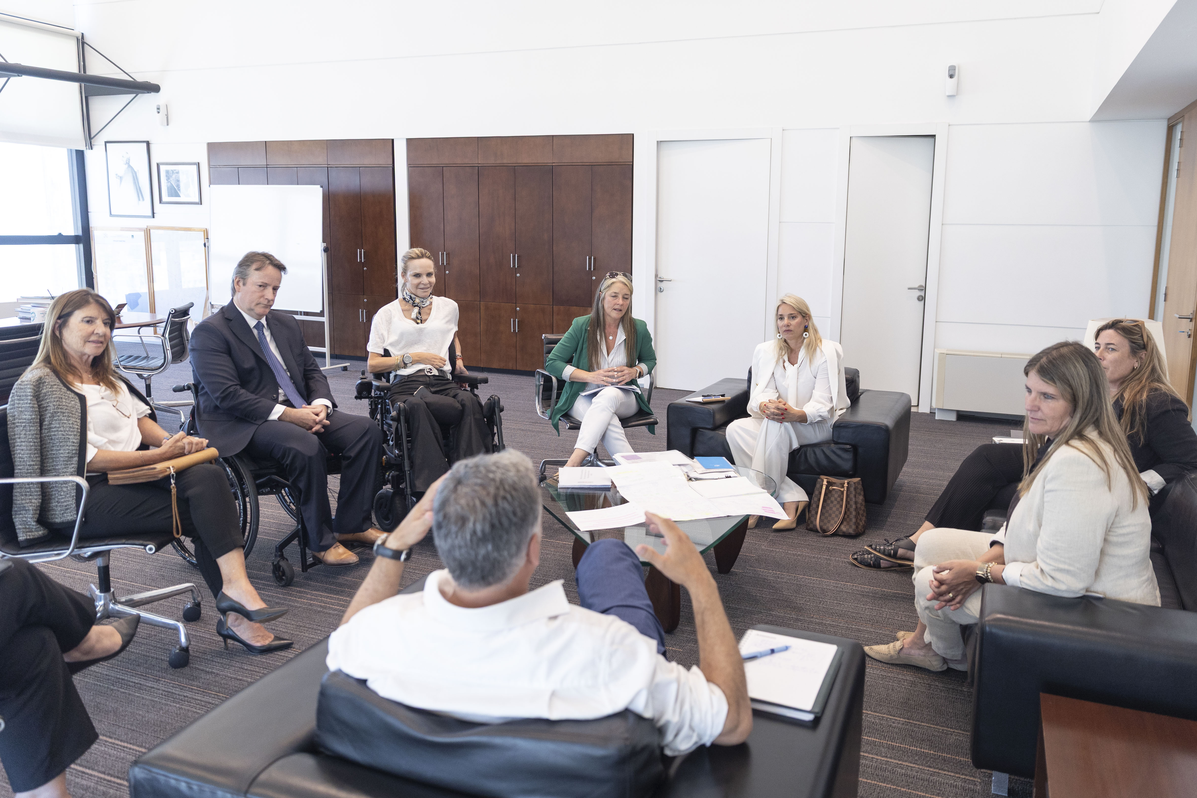 Otra perspectiva de Orsi conversando con los representantes de las fundaciones sentado en círculo en la sala de reuniones.