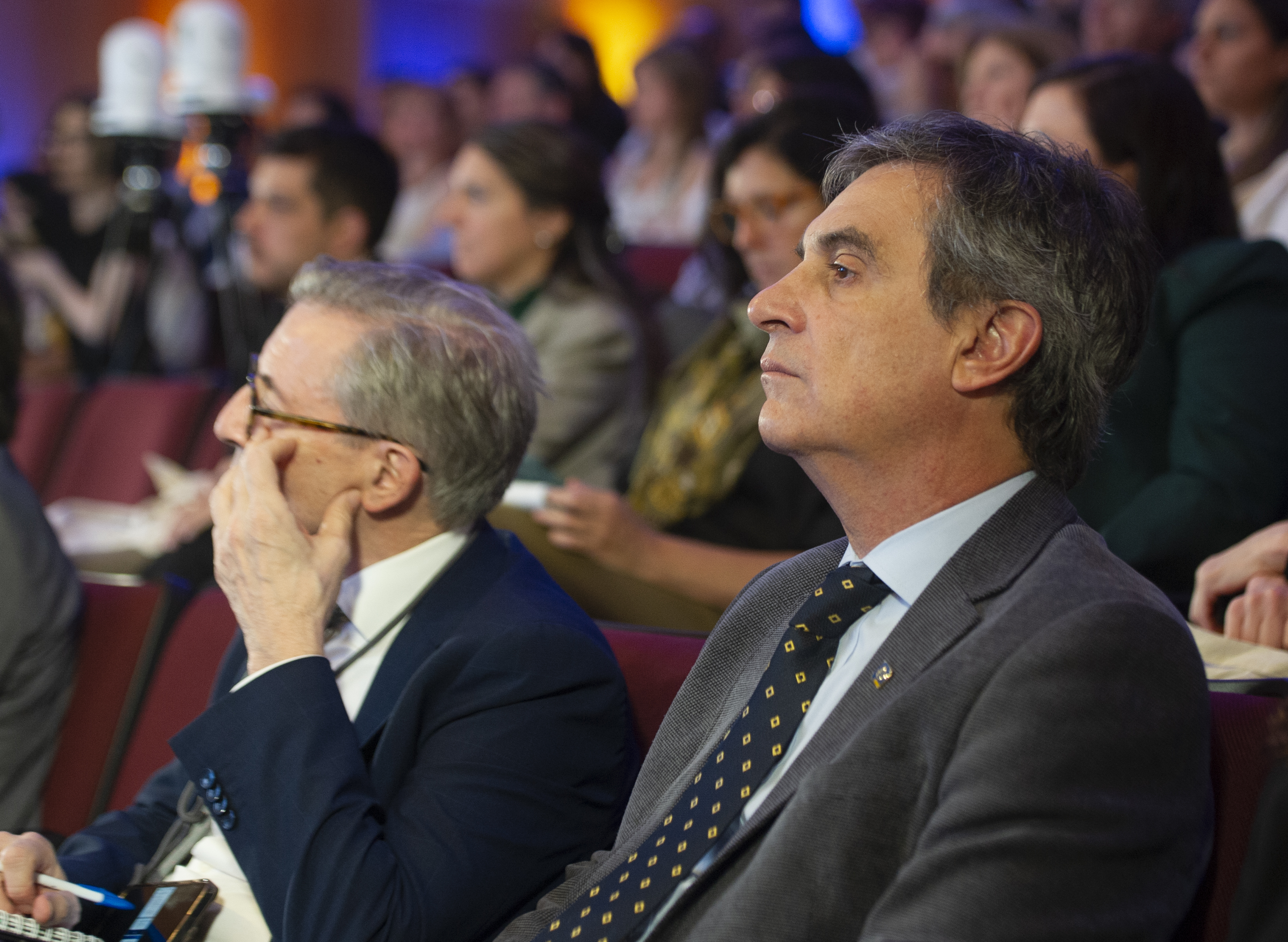 Presidente del BROU sentado en la platea, junto a otros asistentes, escucha una disertación.