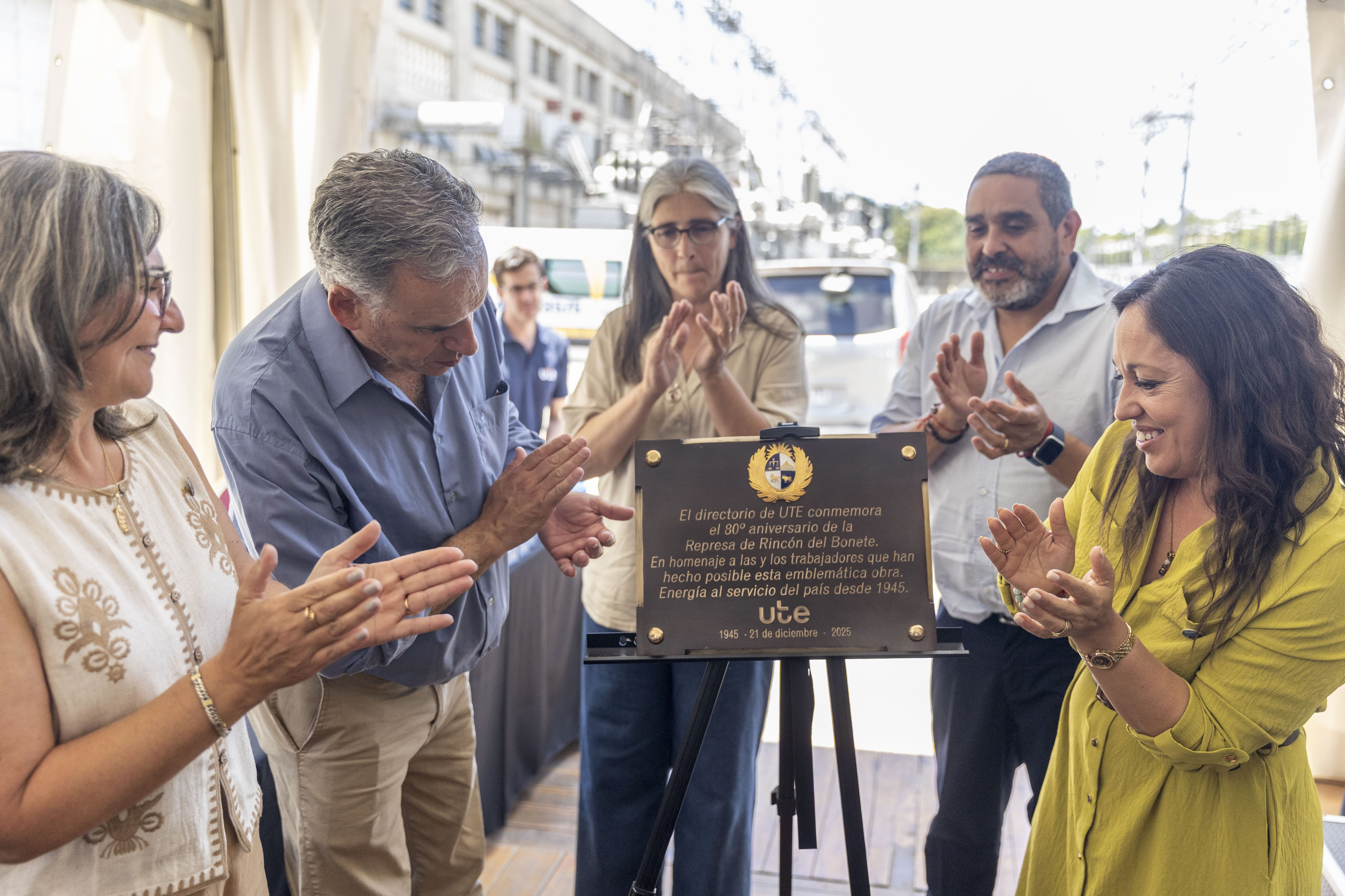 Orsi, las ministras de Industria y Transporte y autoridades de UTE aplauden mientras descubren una placa conmemorativa.