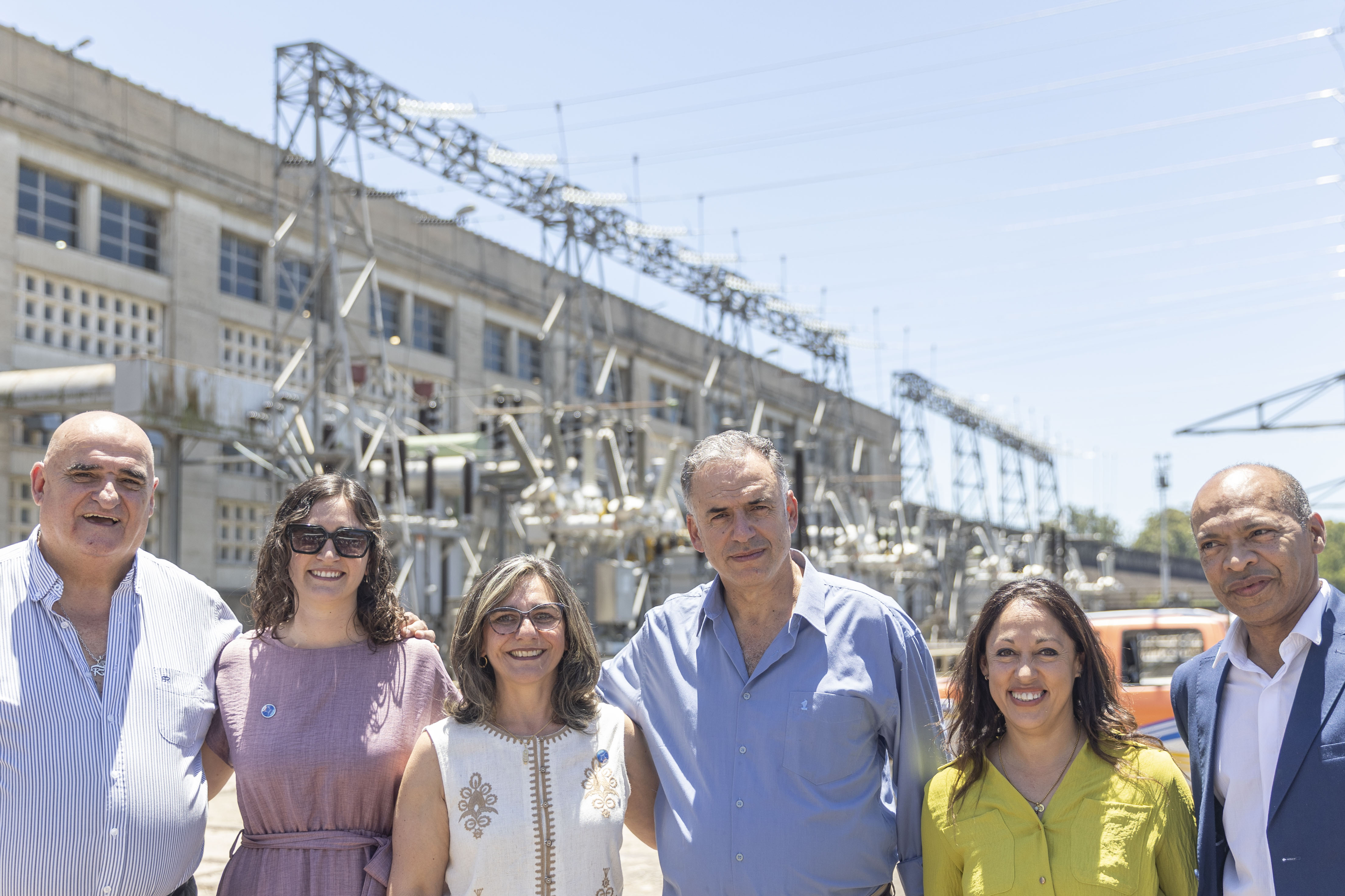 Orsi junto a la ministra de Industria, la presidenta de UTE y otras autoridades posa sonriente frente a cámara al aire libre.