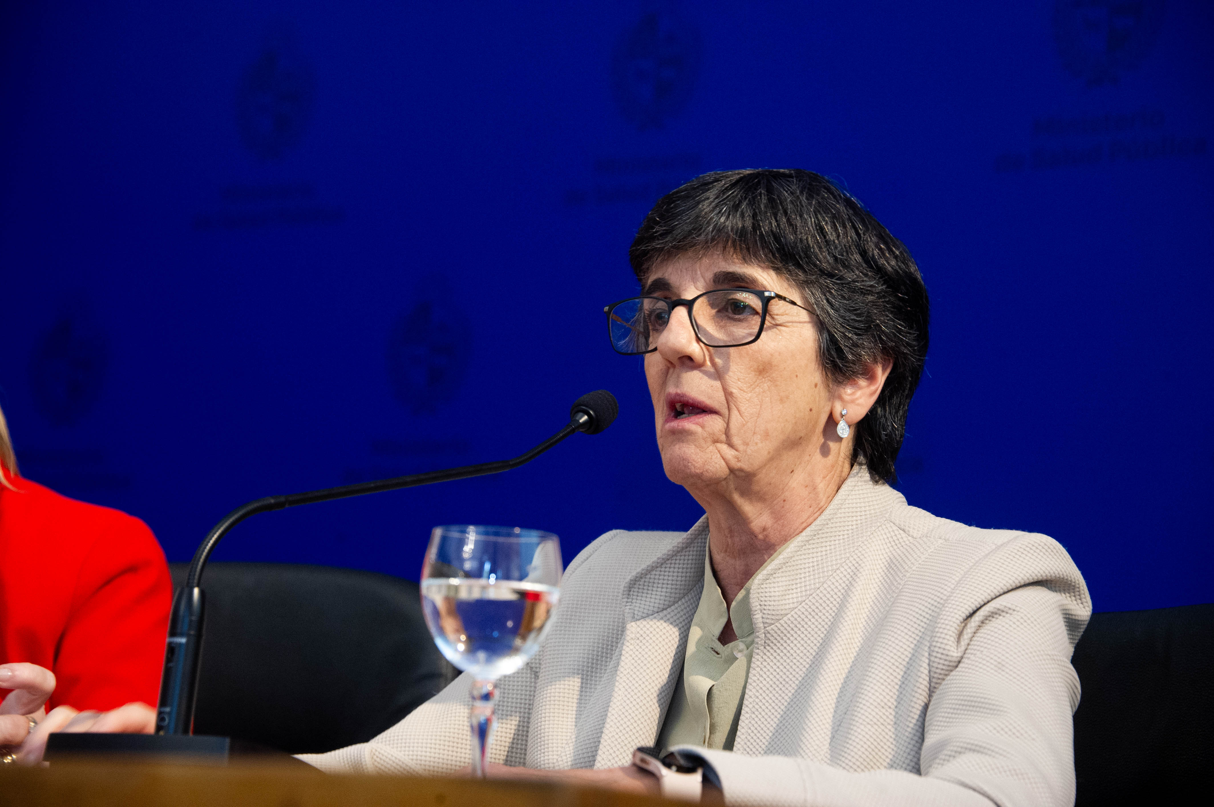 Primer plano de la presidenta del Fondo Nacional de Recursos disertando sentada en mesa con micrófono. Atrás hay un fondo azul.