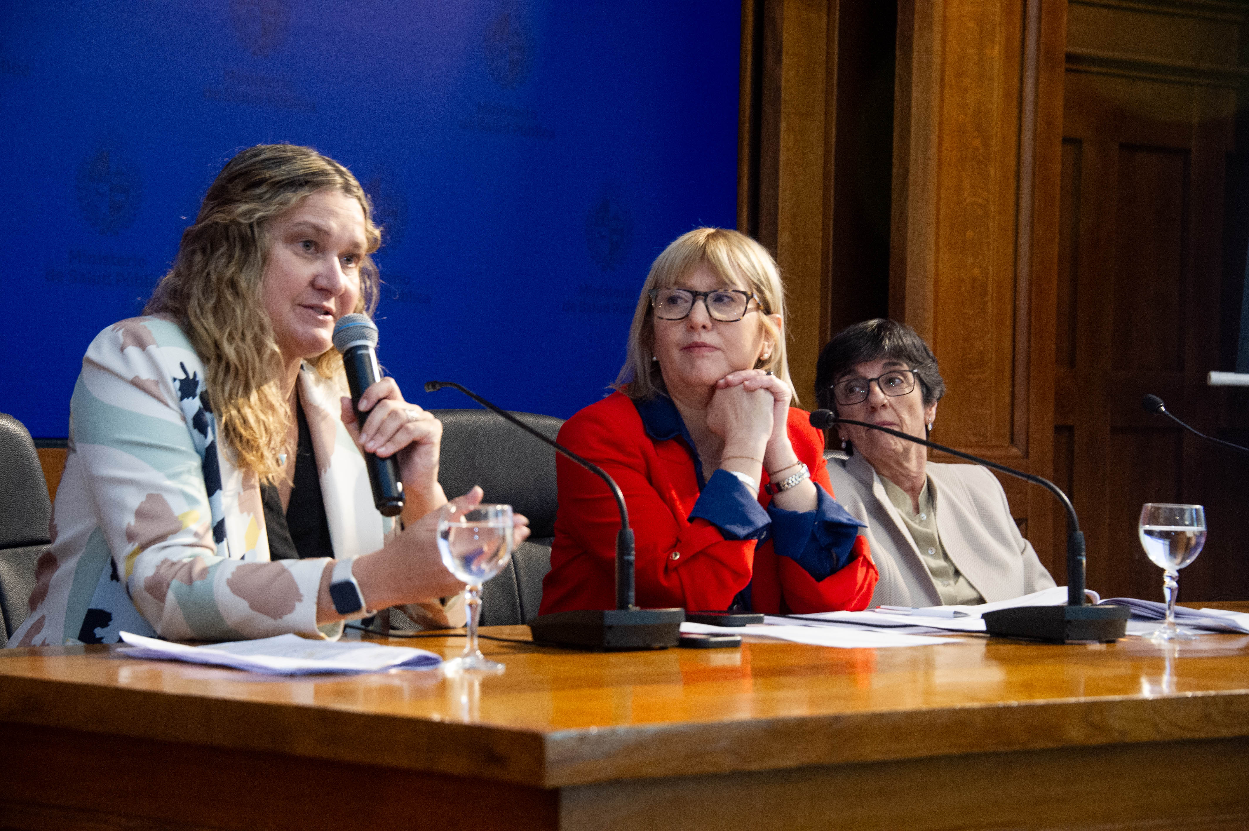 Directora del Fondo Nacional de Recursos diserta sentada con micrófono en mano mientras las otras autoridades la observan.